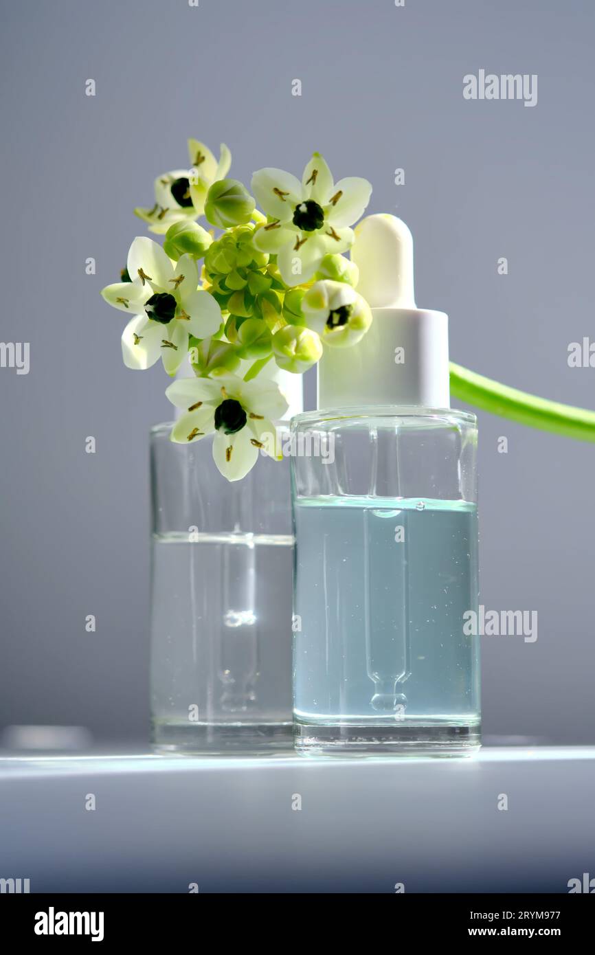 Deux bouteilles avec un compte-gouttes avec des fleurs printanières. Banque D'Images