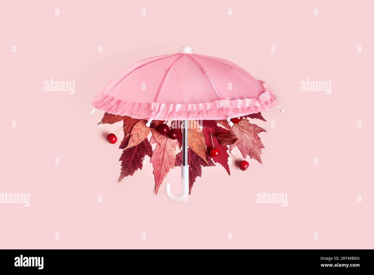Les feuilles d'automne tombent du parapluie rose sur fond pastel rose. Concept créatif Hello Autumn Banque D'Images