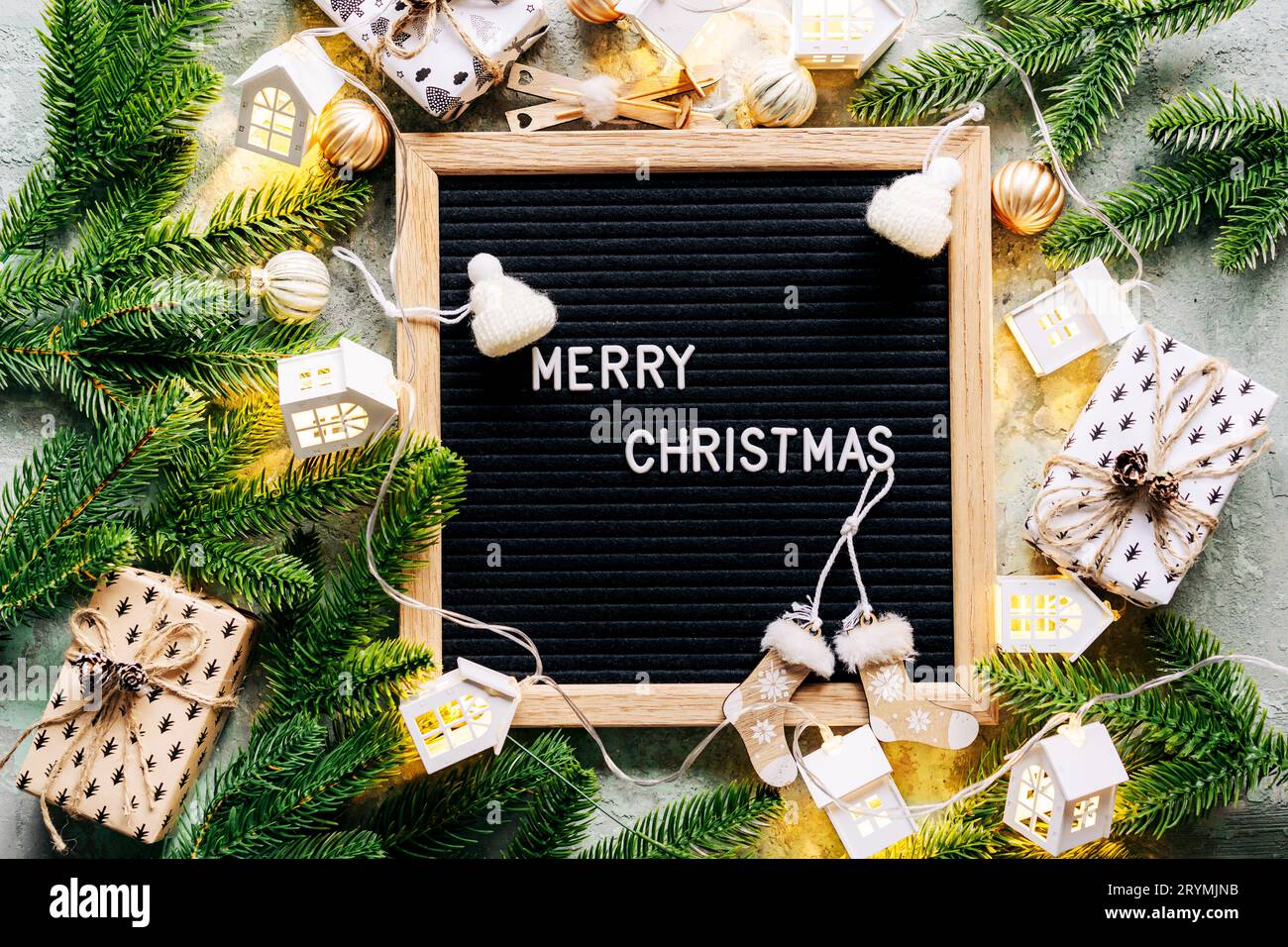 Tableau de lettrage noir avec le Joyeux NOËL de félicitation encadré par des décorations et des branches de sapin. Banque D'Images