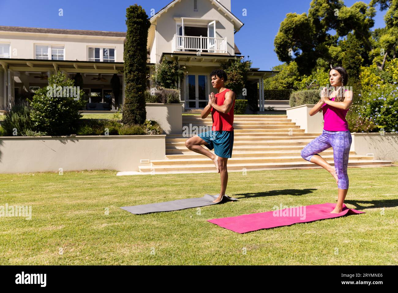 Joyeux couple de forme diverse pratiquant le yoga debout sur une jambe dans le jardin ensoleillé, espace de copie Banque D'Images