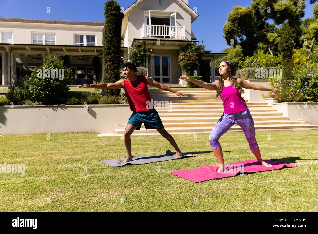 Joyeux couple de forme diverse pratiquant le yoga debout et s'étirant dans le jardin ensoleillé Banque D'Images