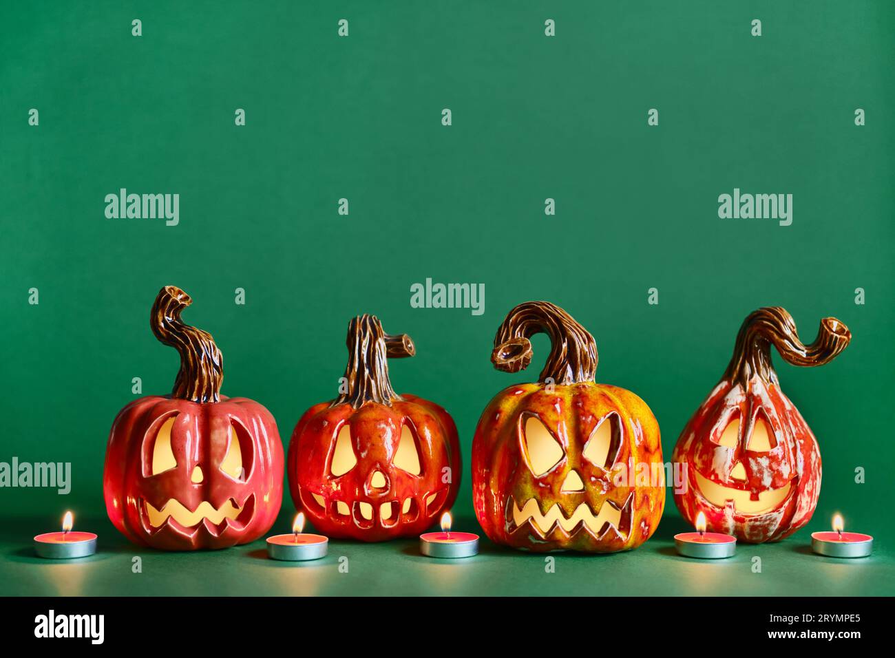 Halloween diy citrouilles en céramique Jack lanterne et bougies sur fond vert pin, espace de copie Banque D'Images