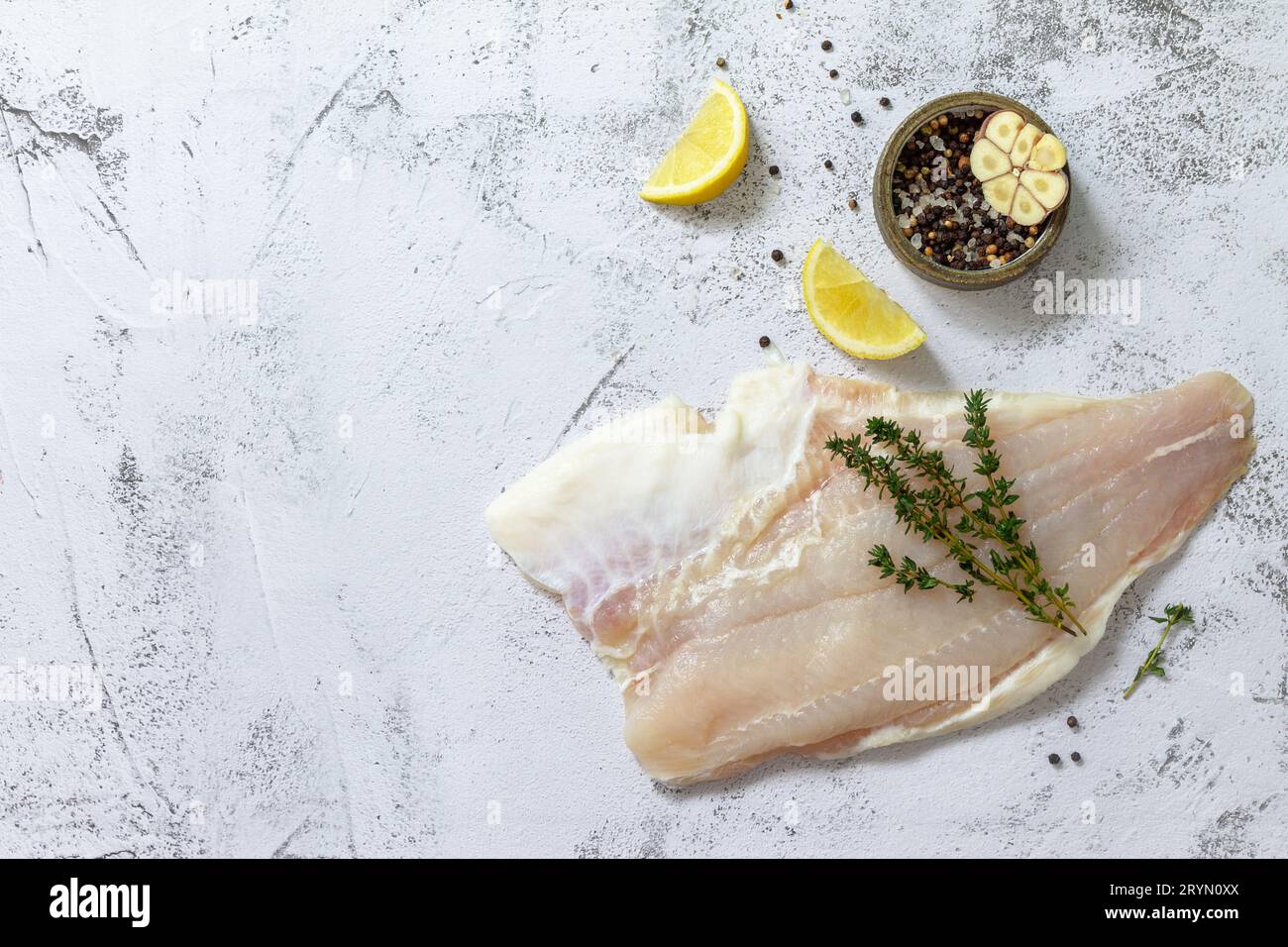 Fruits de mer, filet de poisson blanc cru pour la cuisson. Filet frais Pangasius aux épices, citron et thym sur fond de pierre. Vue de dessus Banque D'Images