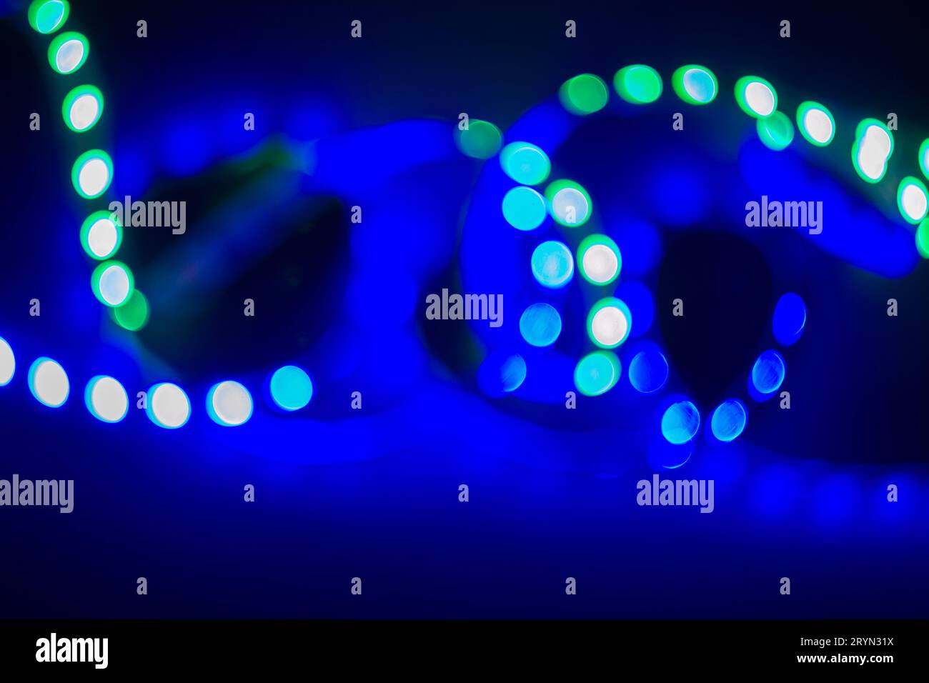 Boucles floues au néon vert et bleu de lumières LED bokeh sur noir. Arrière-plan abstrait Banque D'Images
