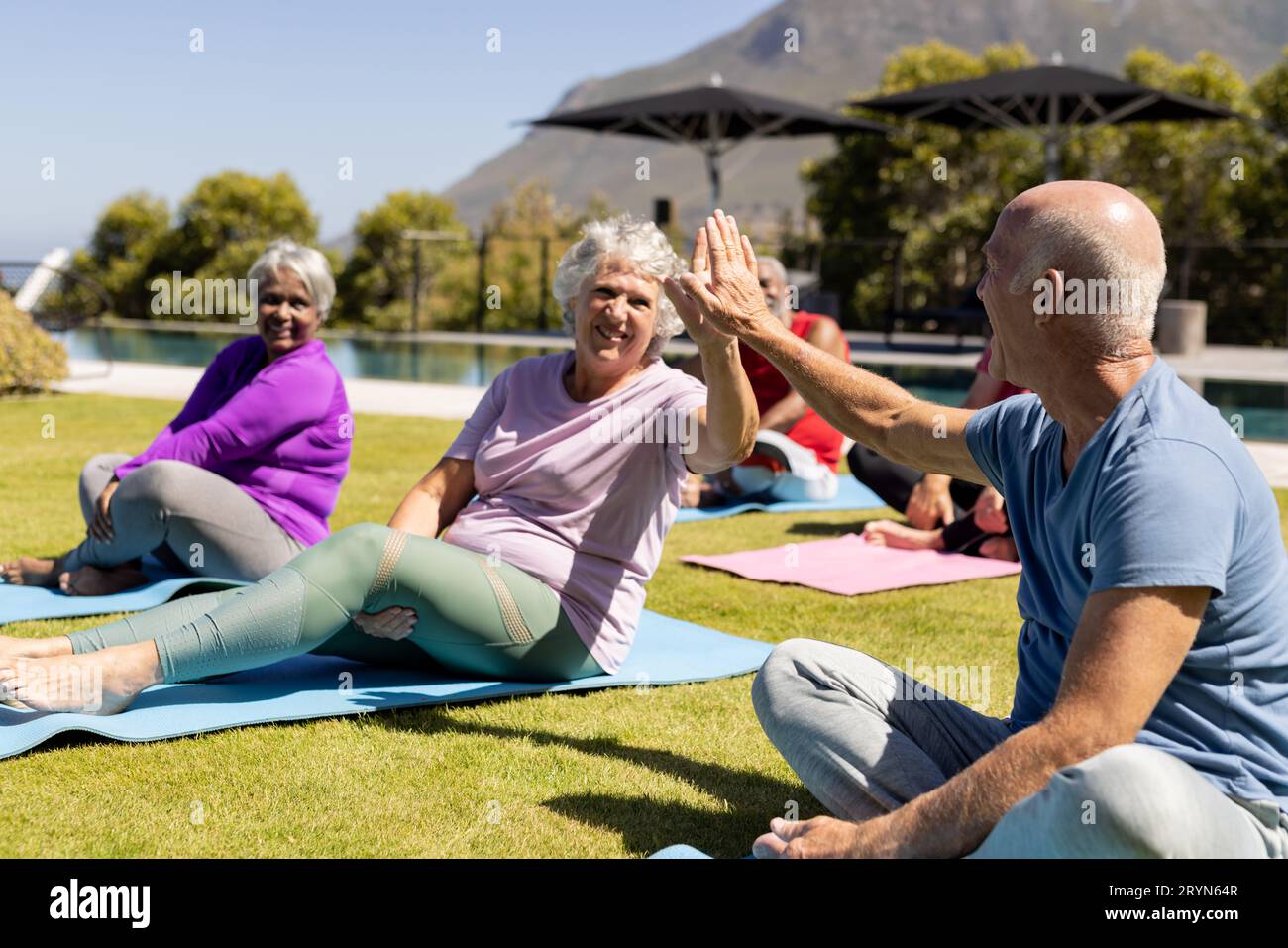 Joyeux amis âgés divers pratiquant le yoga et les hautes performances dans un jardin ensoleillé Banque D'Images