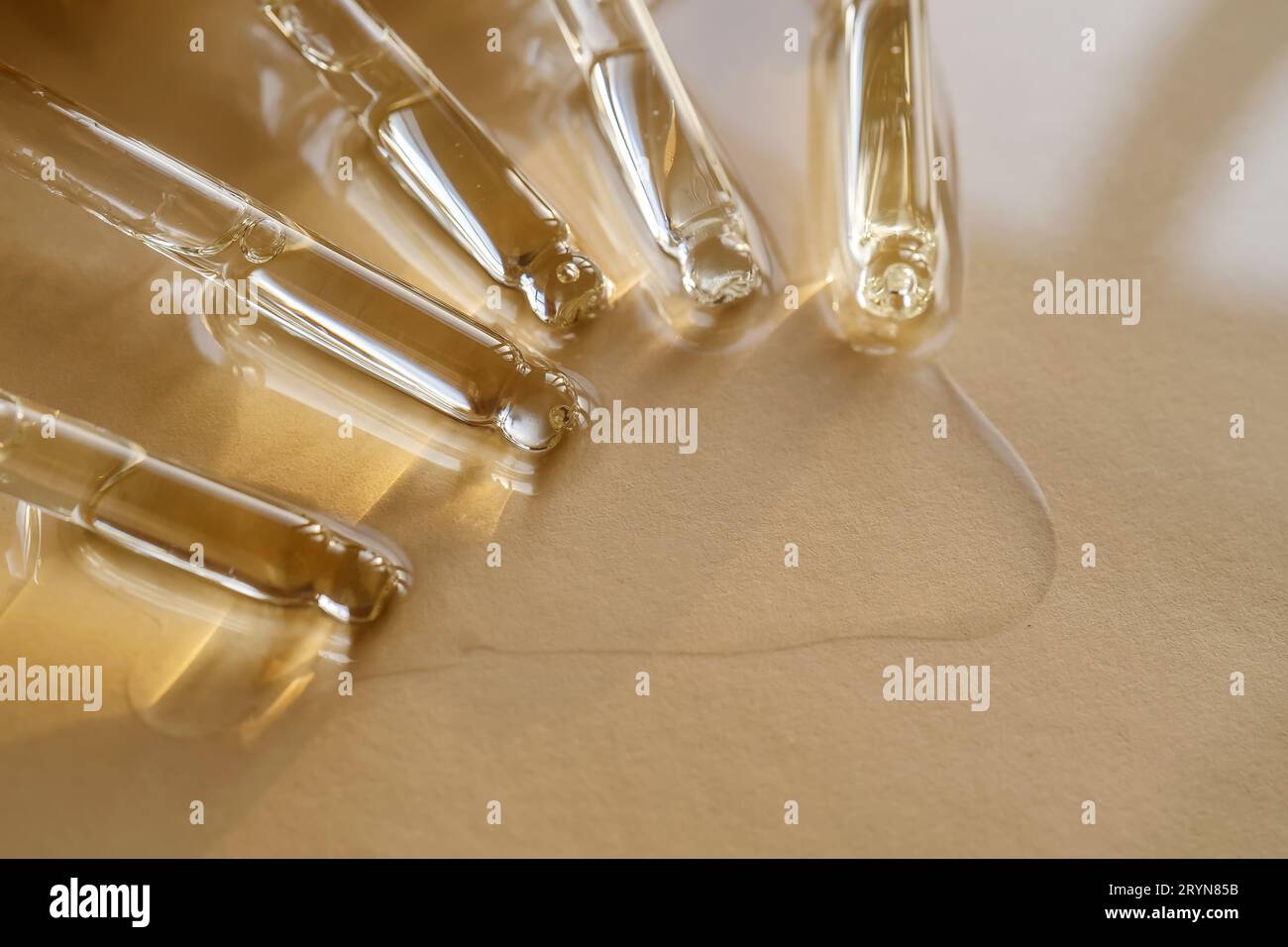 Pipettes avec huile ou sérum sur fond doré. Banque D'Images
