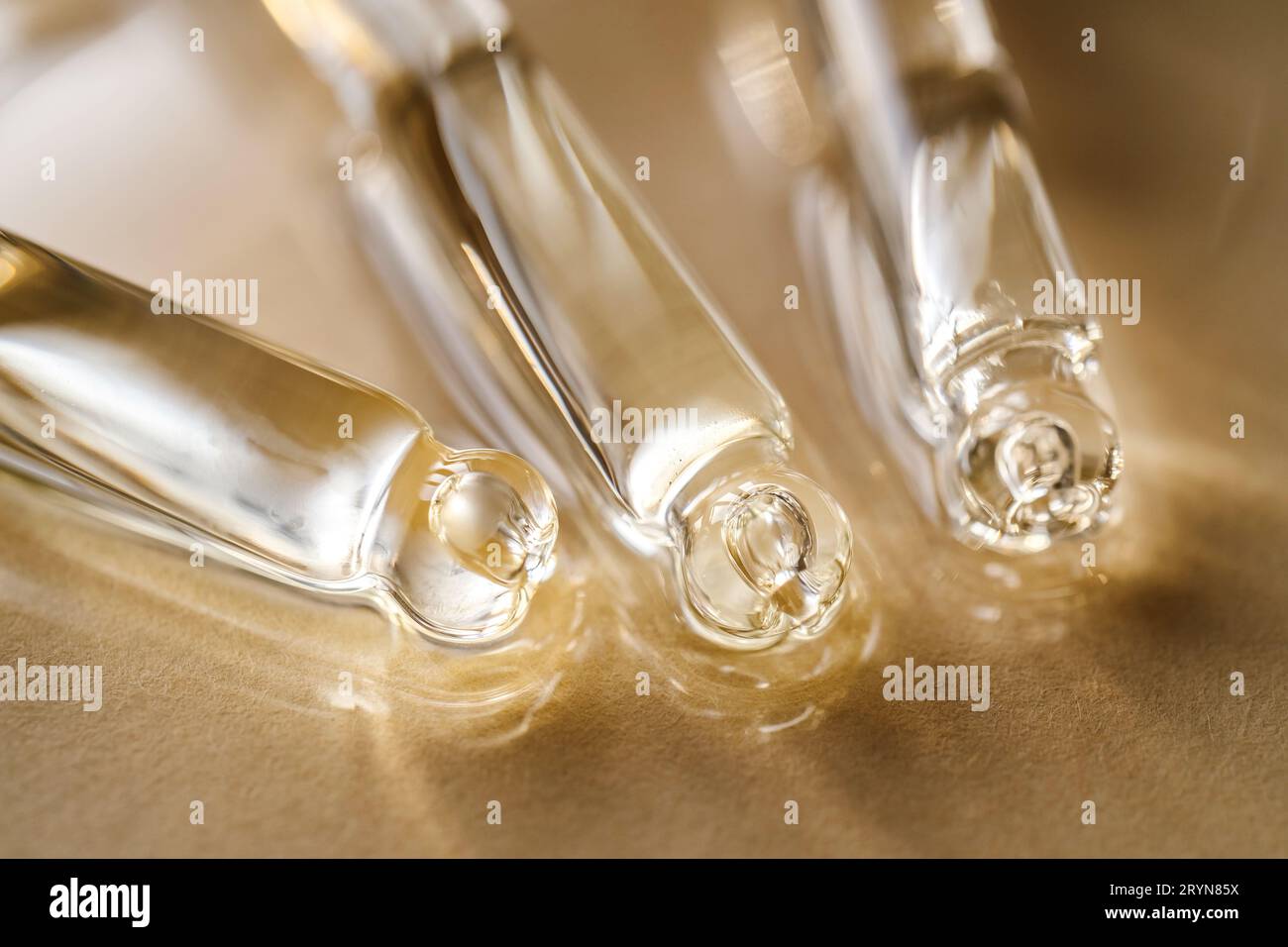 Pipettes avec huile ou sérum sur fond doré. Banque D'Images
