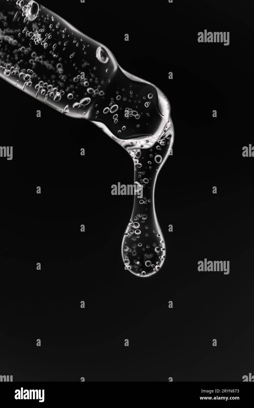 Pipette transparente avec cosmétiques sur fond noir. Banque D'Images