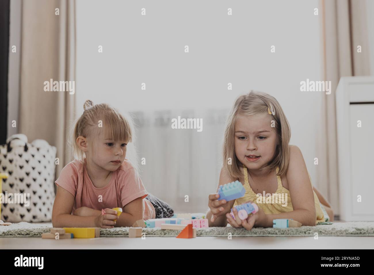 Enfants jouant avec des jouets colorés. Enfants assis sur la moquette dans la chambre à coucher ou la maternelle à la maison, la crèche. Jeu écologique éducatif pour enfant. Concent Banque D'Images