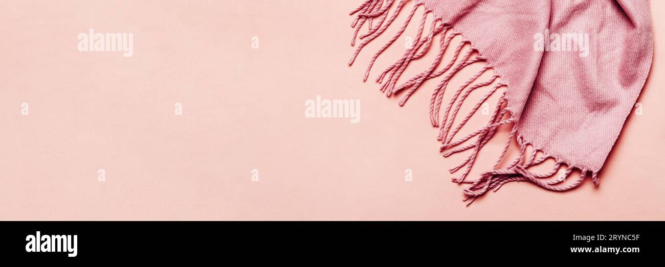 Bannière minimale pour l'hiver ou l'automne. Foulard rose confortable avec glands sur fond pastel Banque D'Images