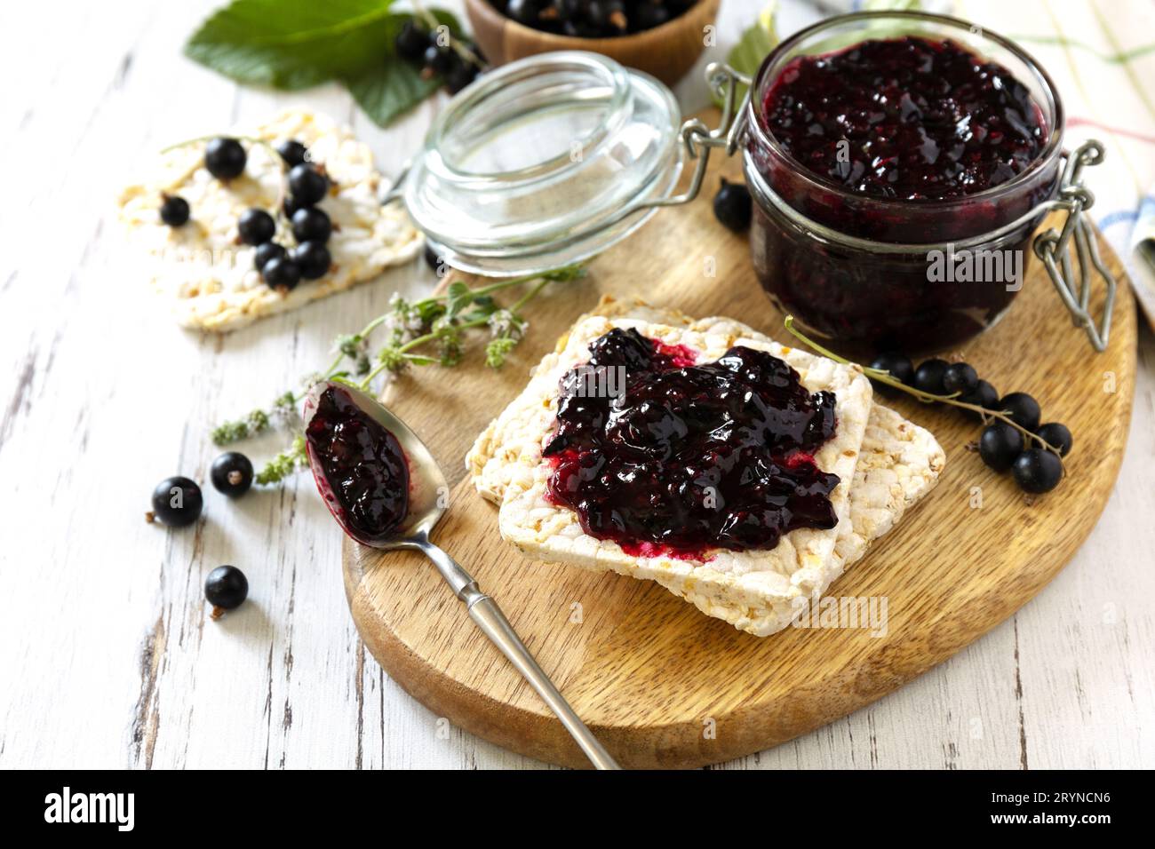 Confiture de cassis dans un pot en verre et pain croustillant sans gluten sur une table rustique. Banque D'Images