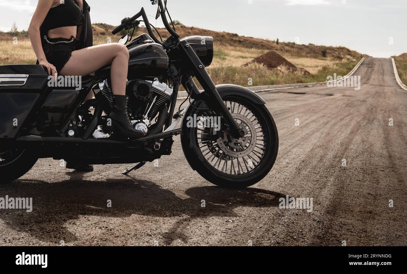 Sexy femme portant de hauts talons noirs en train de monter une moto de rue à l'extérieur. Exploration et aventure, vélo de rue Banque D'Images