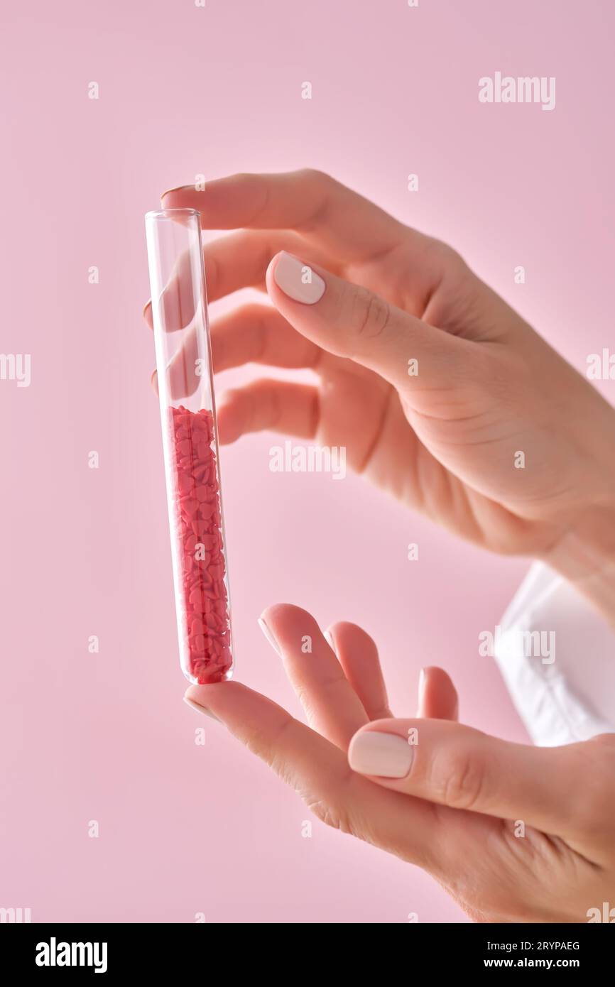 La fille tient un tube à essai avec des coeurs rouges. Banque D'Images