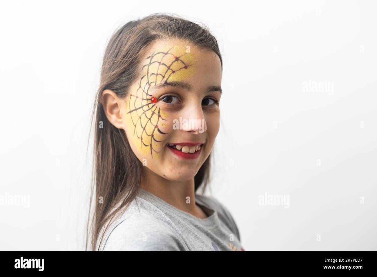 Belle fille adolescente aux yeux bruns, cheveux longs, sourire et regarder vers le bas dans un chapeau vert avec araignées noires et toile pour la fête de costume, avec maquillage d'eau Banque D'Images