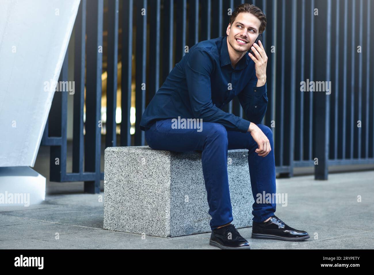Un homme souriant parle au téléphone dans la rue ville Banque D'Images