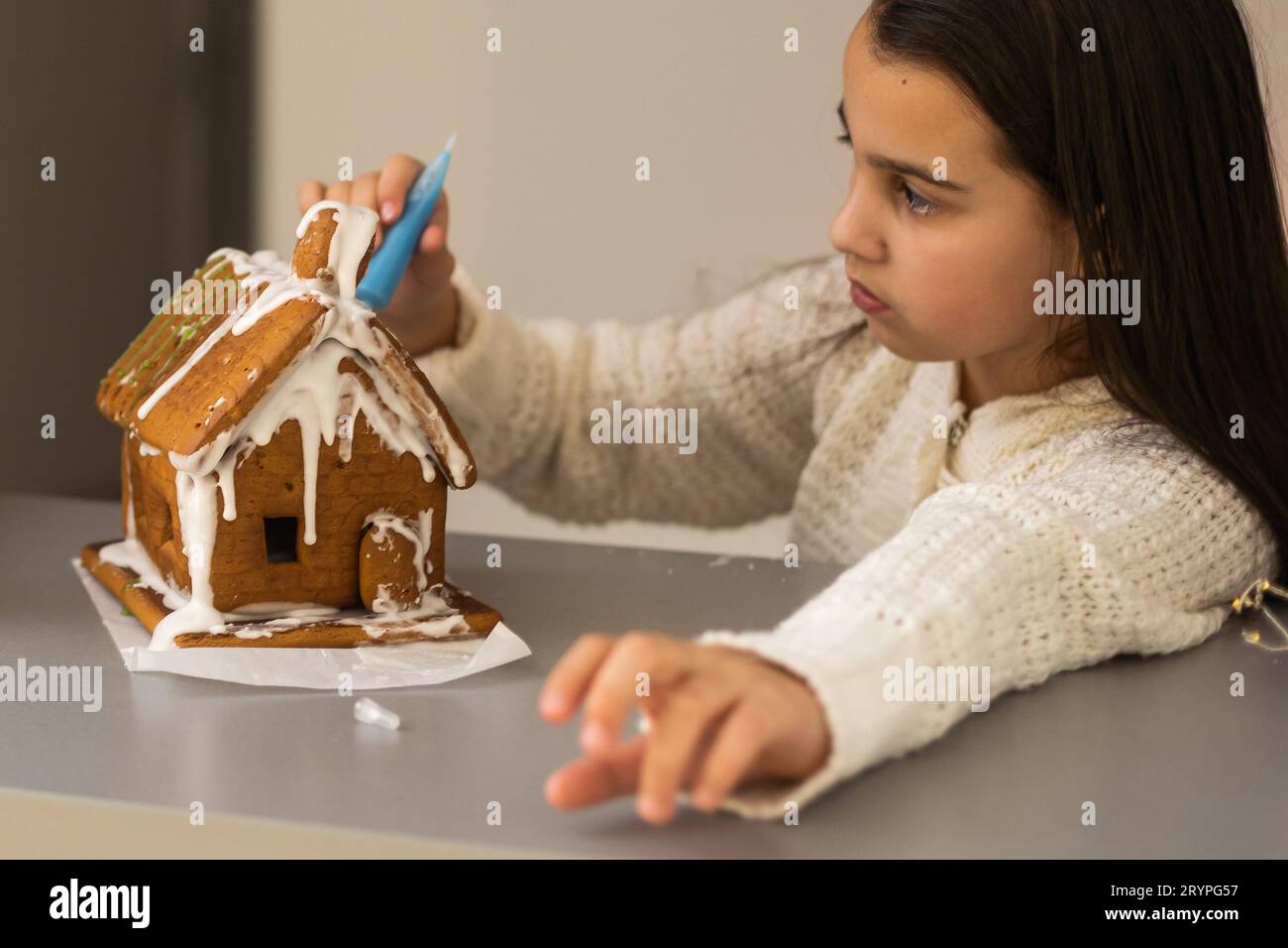 Une fille joue avec une maison de pain d'épice pour la décoration de Noël traditionnelle Banque D'Images