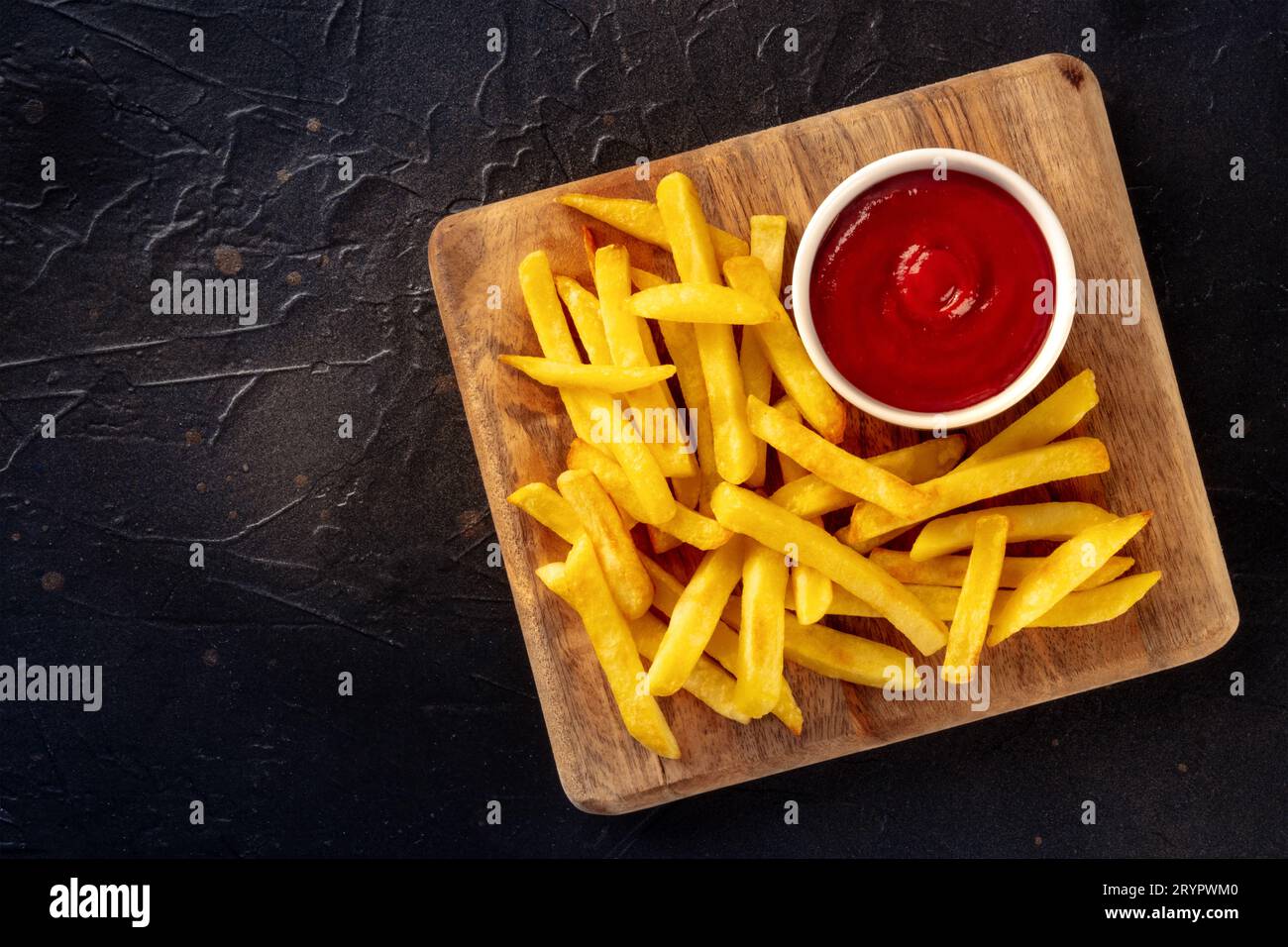 Frites, en-cas de pommes de terre au ketchup, restauration rapide sur fond d'ardoise noire, prise par le dessus avec un espace pour le texte Banque D'Images