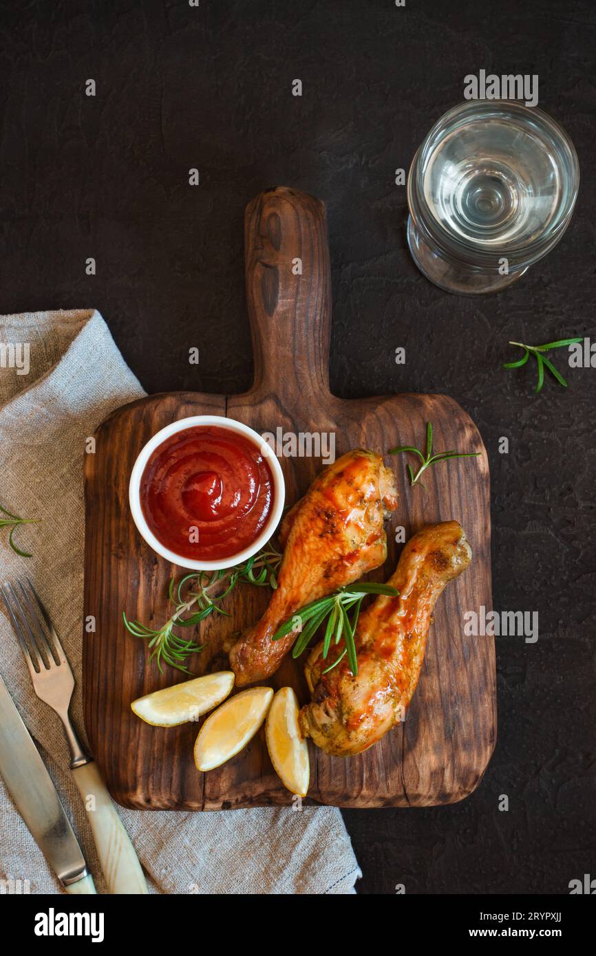 Le pilon de poulet épicé grillé est servi sur une planche de bois. Haut Banque D'Images