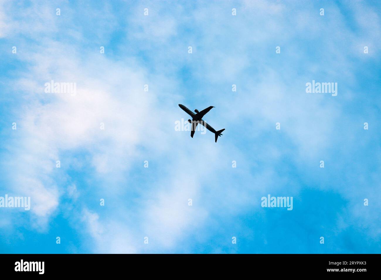 Avion unique volant à travers un ciel bleu nuageux jour Banque D'Images