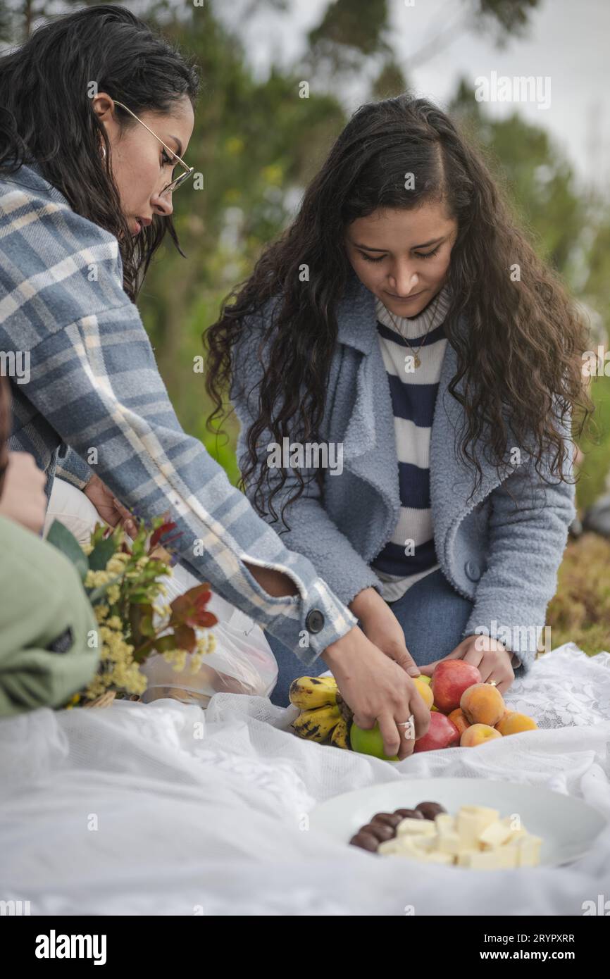 Jeunes femmes latines cueillant des fruits lors d'une journée de pique-nique dans la nature Banque D'Images
