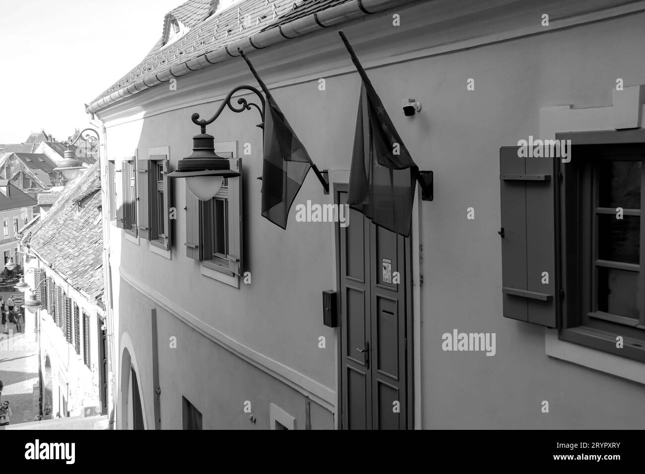 Drapeau de la Roumanie et drapeau de l'Union européenne accroché à un mur sur un bâtiment à Sibiu en noir et blanc Banque D'Images