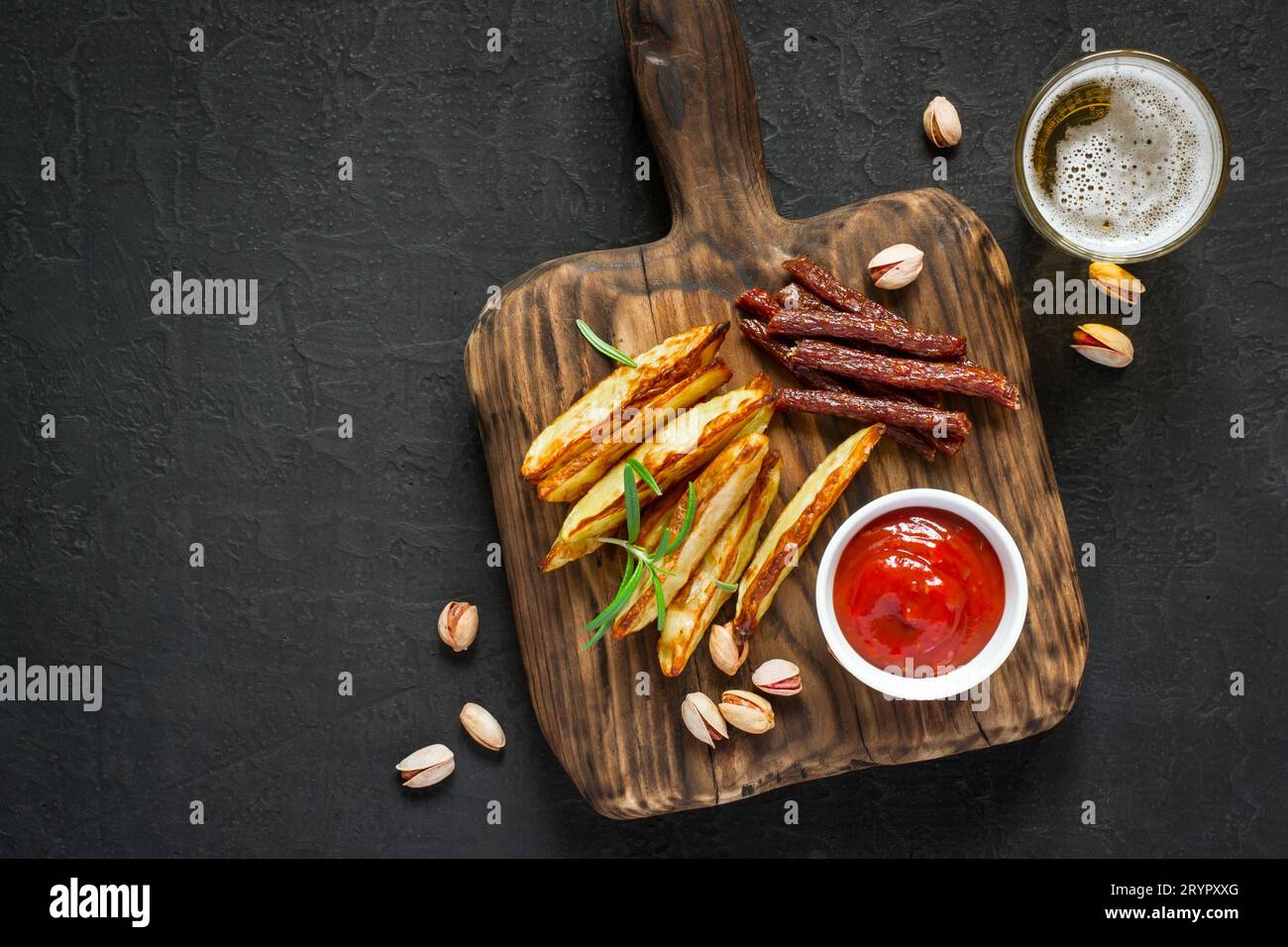 Snacks variés pour la bière. Pommes de terre frites pepperoni noix et un verre de bière Banque D'Images