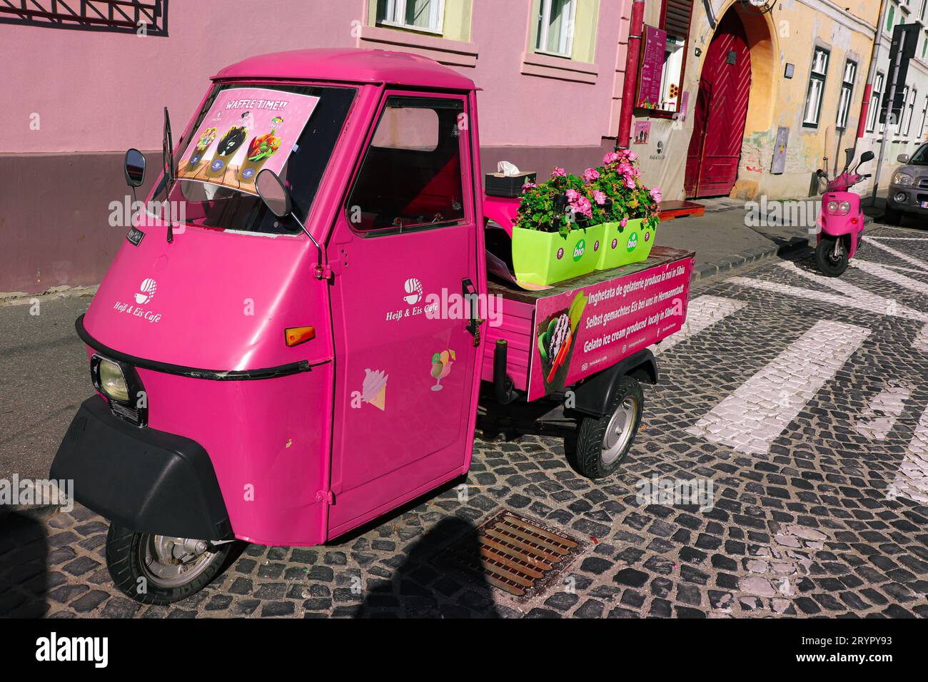 Heiss et EIS Cafe, le plus petit café de Sibiu. Fenêtre avant pour commander et un pousse-pousse auto rose (Tuk tuk) Banque D'Images