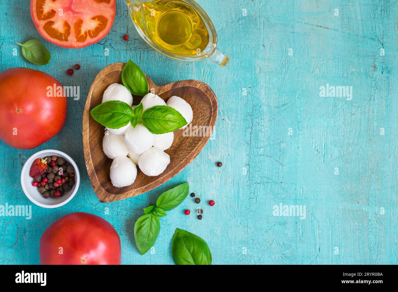 Fromage mozzarella, tomates et basilic sur une table turquoise. Conc Banque D'Images