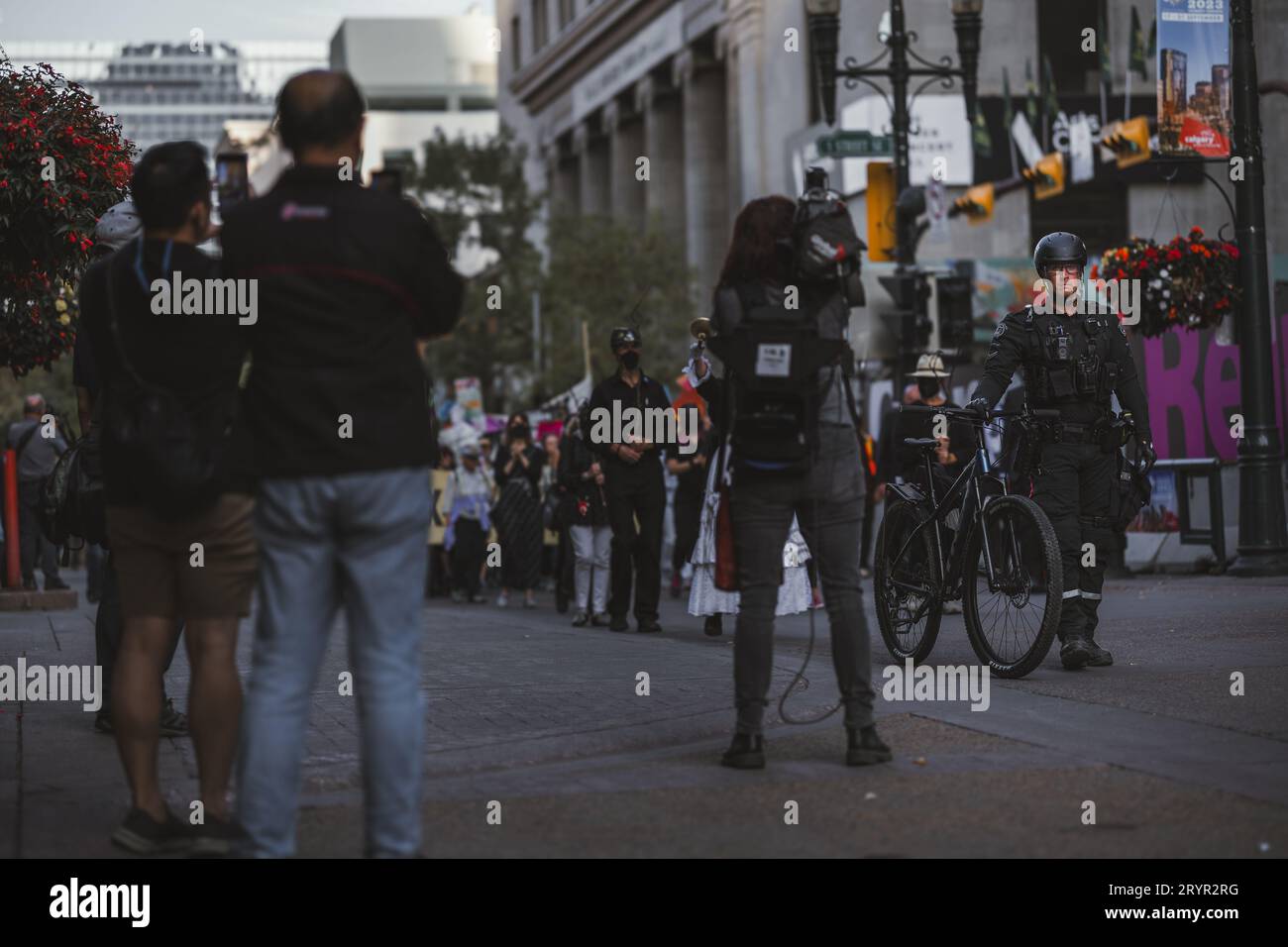 Un opérateur de caméra de presse enregistre un agent de police guidant une manifestation de militants pour le climat pendant le Congrès mondial du pétrole à Calgary Banque D'Images