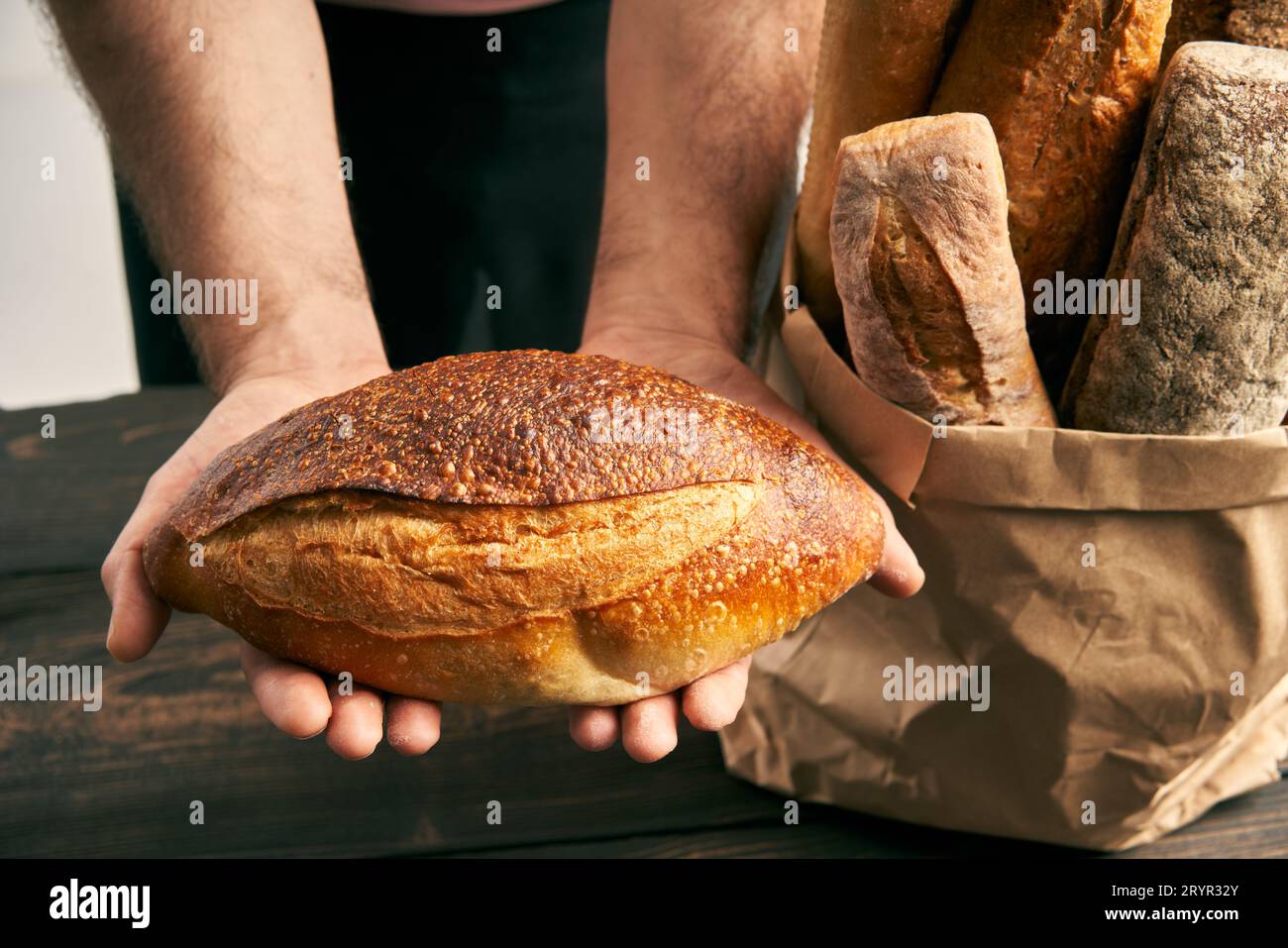 Boulanger en tablier tenant une miche de pain frais dans les mains Banque D'Images