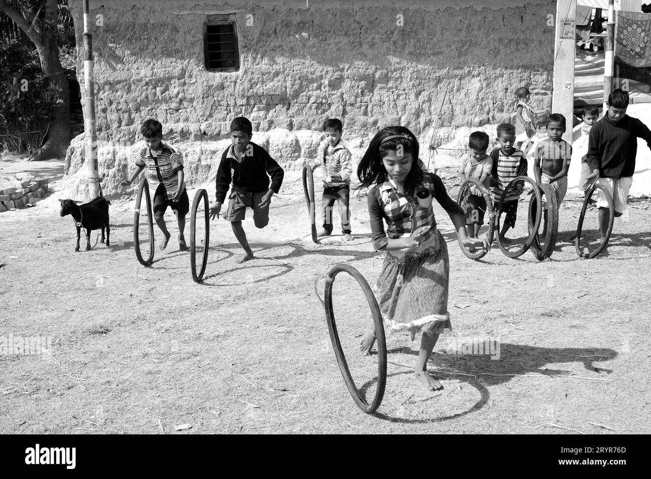 Les enfants du village rural jouent avec des pneus en caoutchouc pour vélo le matin en vacances au Bengale occidental, en Inde. Banque D'Images