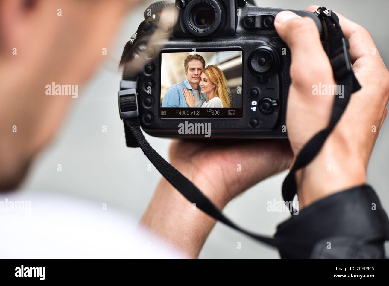 Gros plan les mains masculines tiennent un appareil photo professionnel et font une photo. Banque D'Images