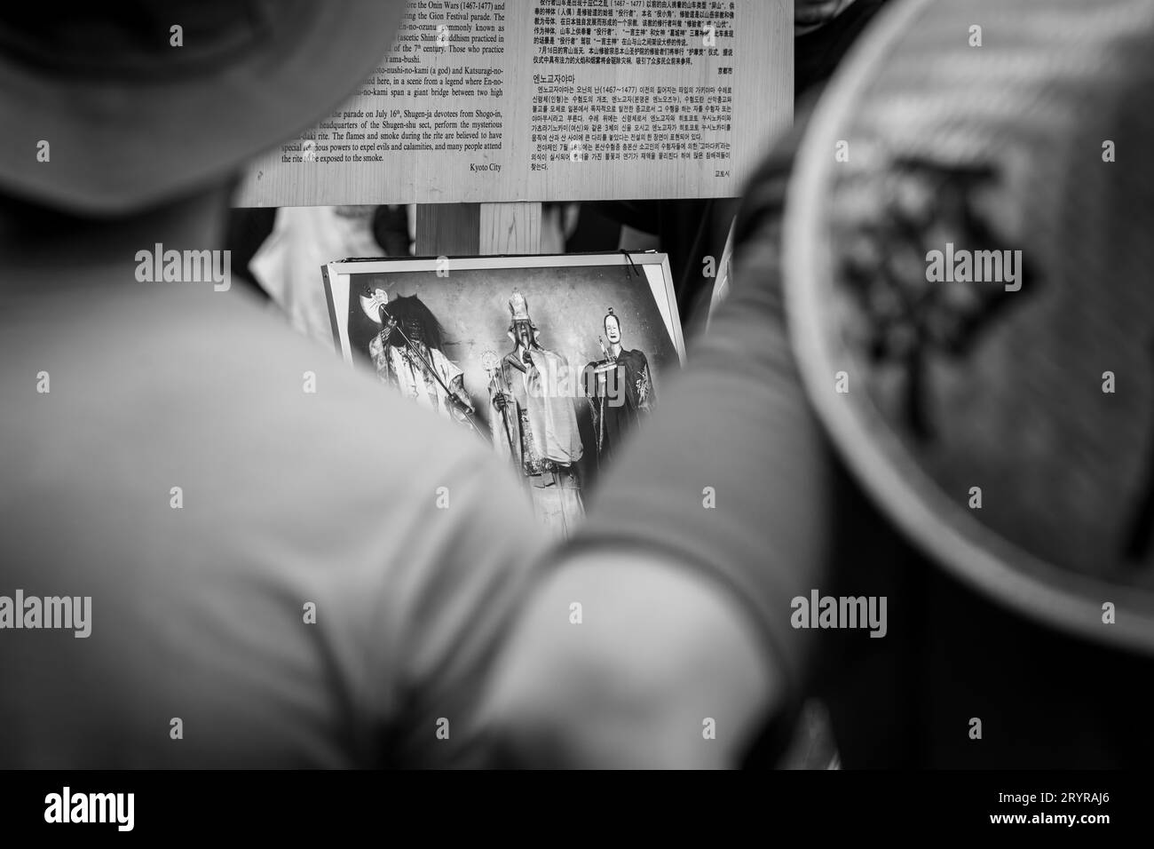 Un jeune adulte portant un chapeau noir se tient face à un mur et tient une photographie encadrée dans sa main droite tout en lisant attentivement le contenu Banque D'Images