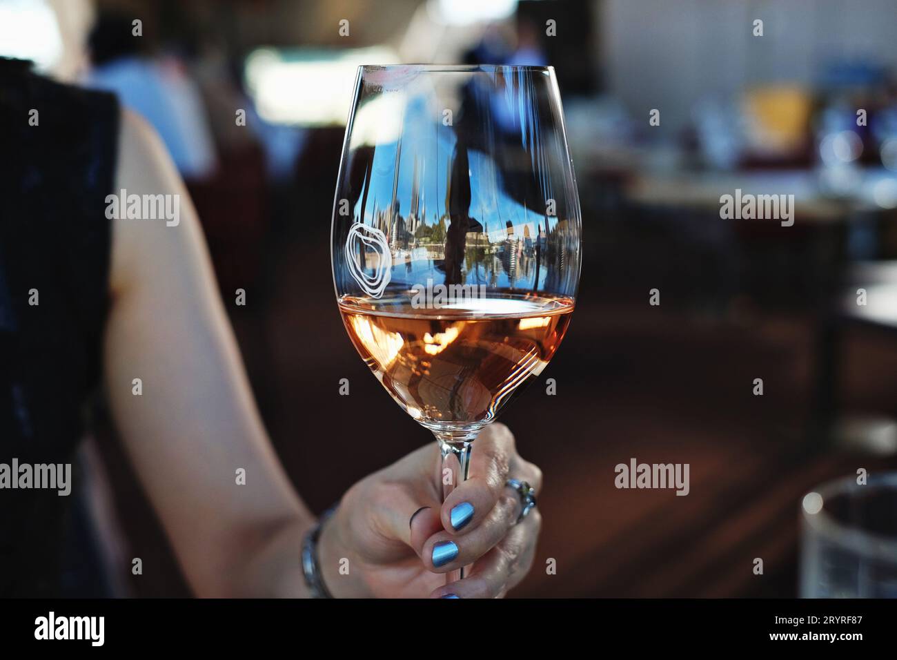 Gastronomie à Sydney avec un verre de vin rosé tenu par une femme dans une main, déjeuner au restaurant Bennelong de l'Opéra de Sydney Banque D'Images