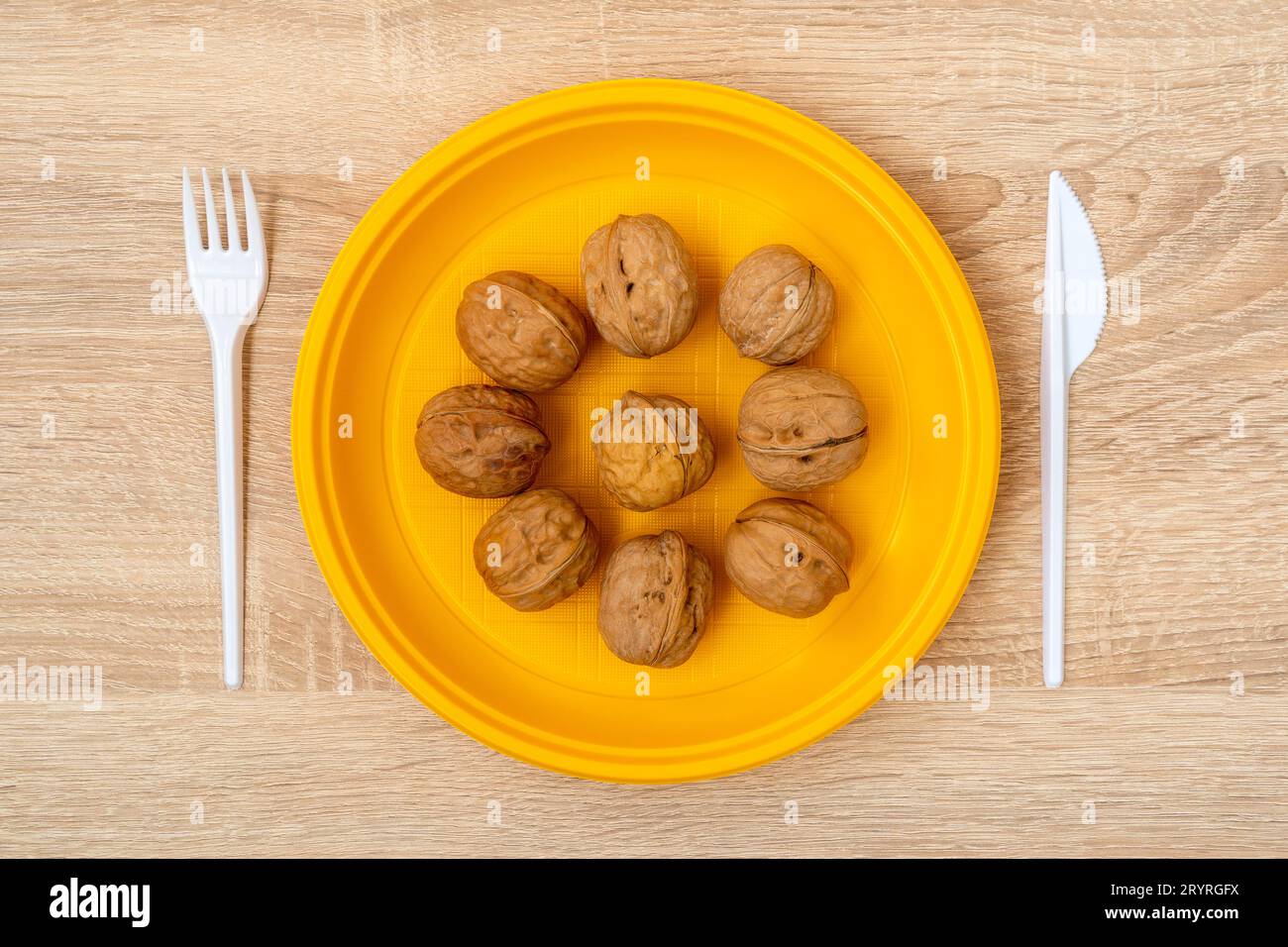 Noix dans une assiette jetable jaune. Concept de nourriture saine. Banque D'Images