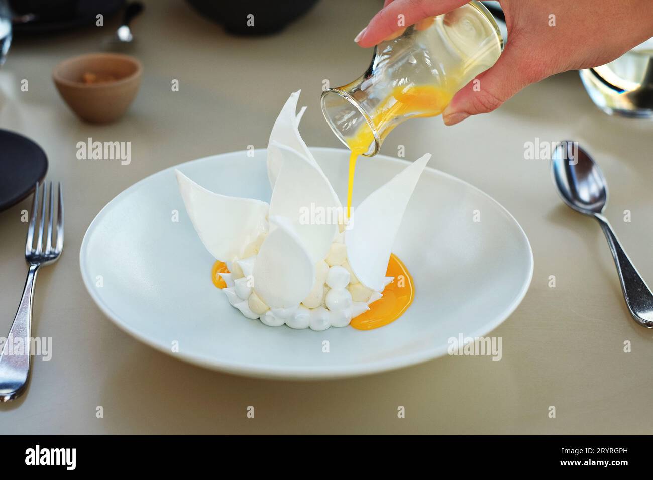 Verser du jus de fruits de la passion frais sur le Bennelong Pavlova par le chef étoilé Peter Gilmore - cuisine fine au Bennelong Restaurant, à l'opéra de Sydney Banque D'Images