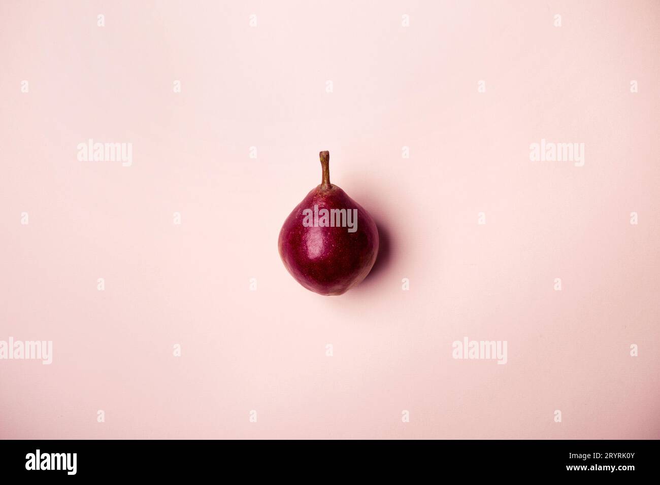 Poire violette rose sur fond rose. Style minimaliste. Concept de récolte d'automne Banque D'Images