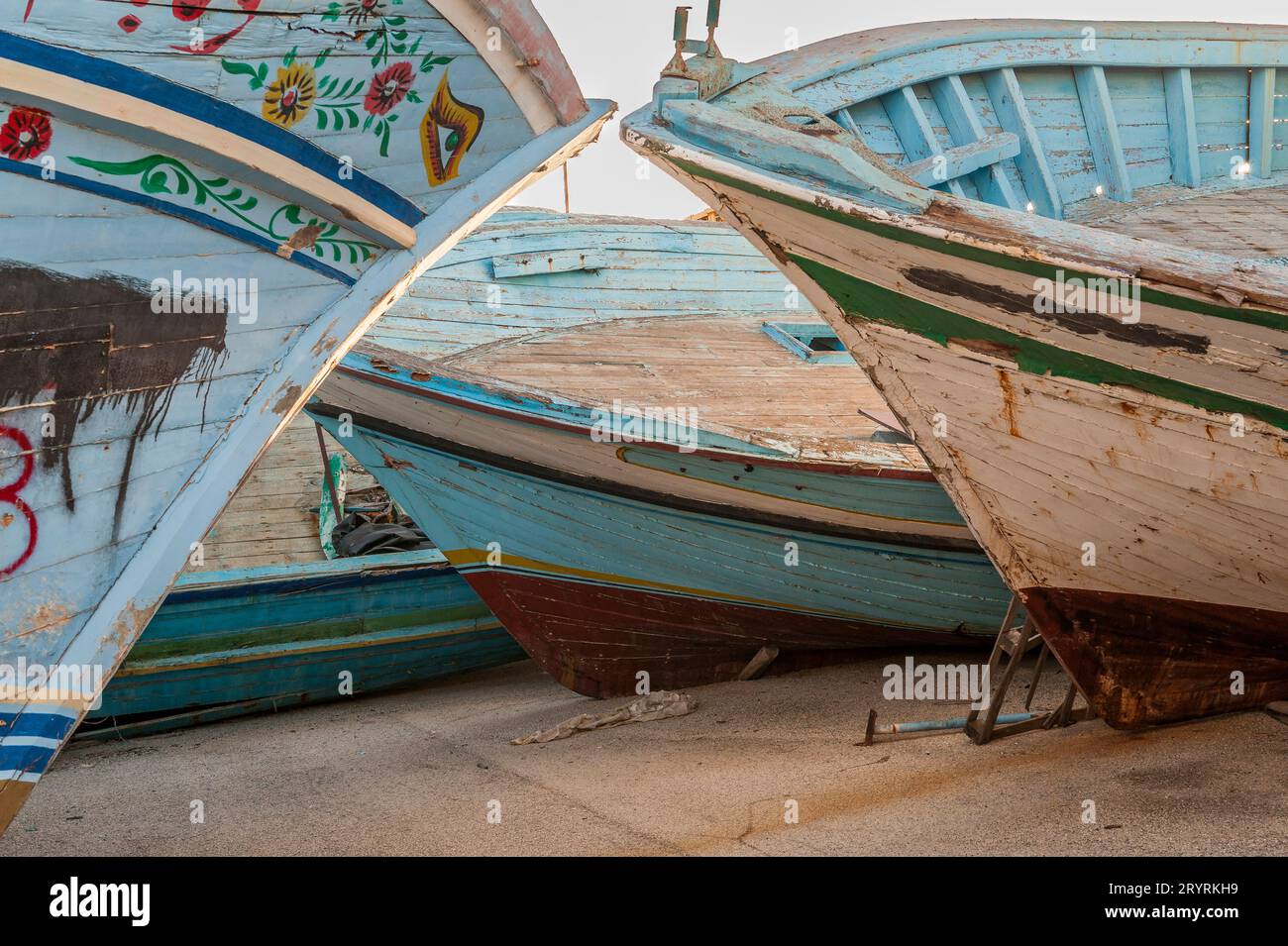 Vieux bateaux de pêche utilisés par les réfugiés et les migrants pour traverser la Méditerranée de l'Afrique du Nord à l'Europe, confisqués par les gardes frontière italiens et stockés au port de Pozzallo, Sicile, Italie. Les symboles peints (en particulier l'œil d'Horus) sont destinés à porter chance et à repousser le mal. Banque D'Images