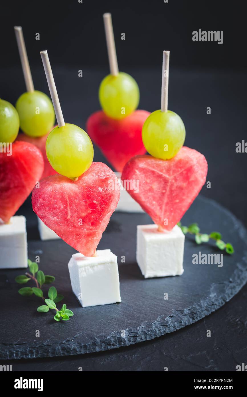 Snack pour la Saint-Valentin. Pastèque, feta et raisins sur brochettes Banque D'Images