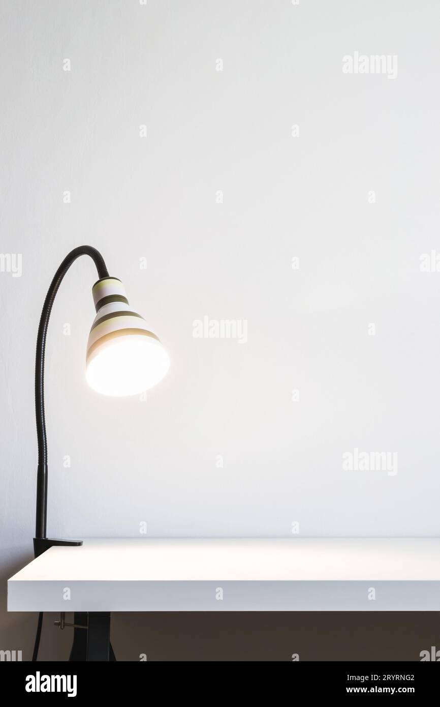 Lampe de table lumineuse sur un bureau blanc. Mur blanc pour espace de maquette ou de copie Banque D'Images