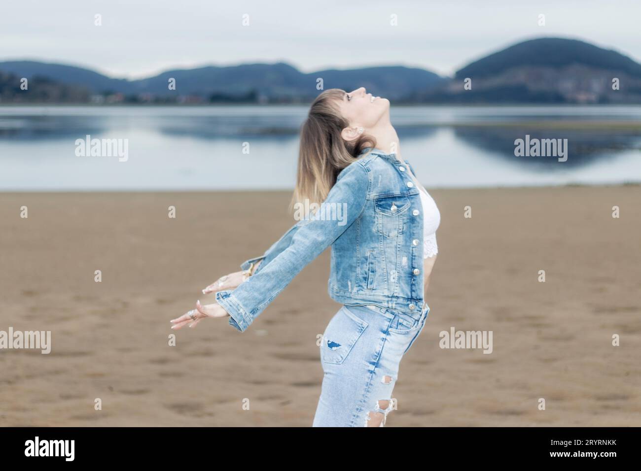 Coastal Mindfulness : Femme magnifique embrassant la paix et la respiration profonde par l'océan en hiver Banque D'Images