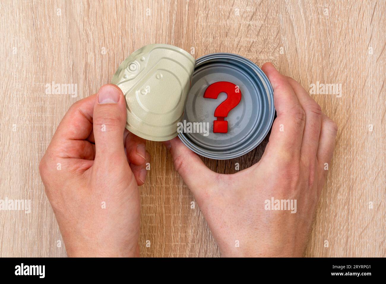 Les mains ouvrent boîte de conserve dans laquelle est un point d'interrogation Banque D'Images