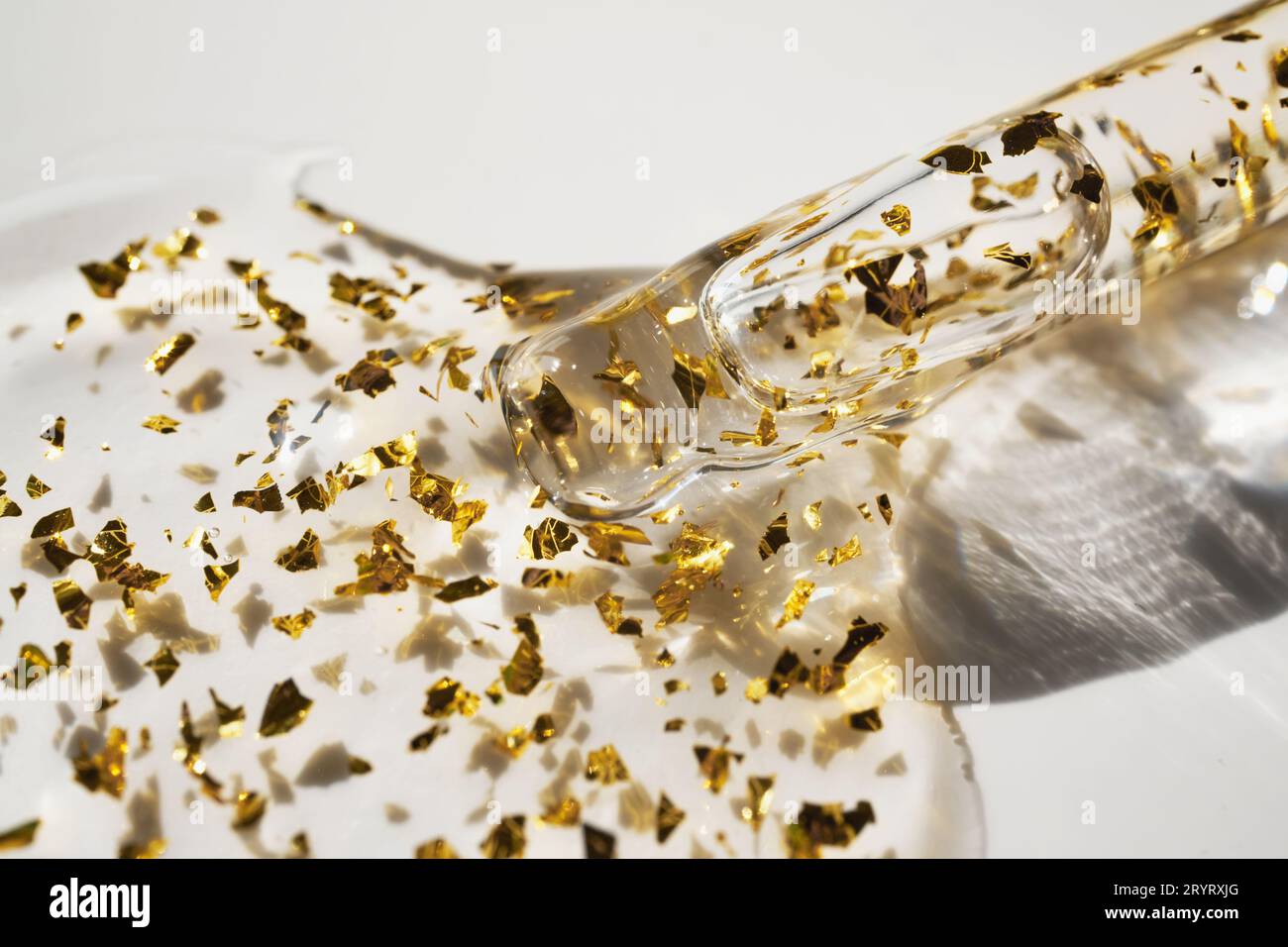 Pipette et goutte de produit cosmétique avec des particules d'or, foyer sélectif Banque D'Images