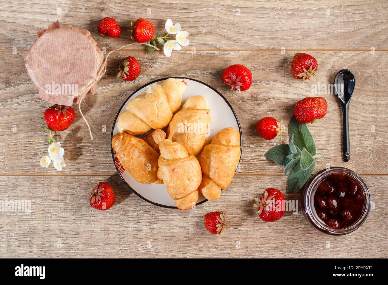 Confiture traditionnelle de fraises maison dans un bocal et croissants sur les planches de bois Banque D'Images