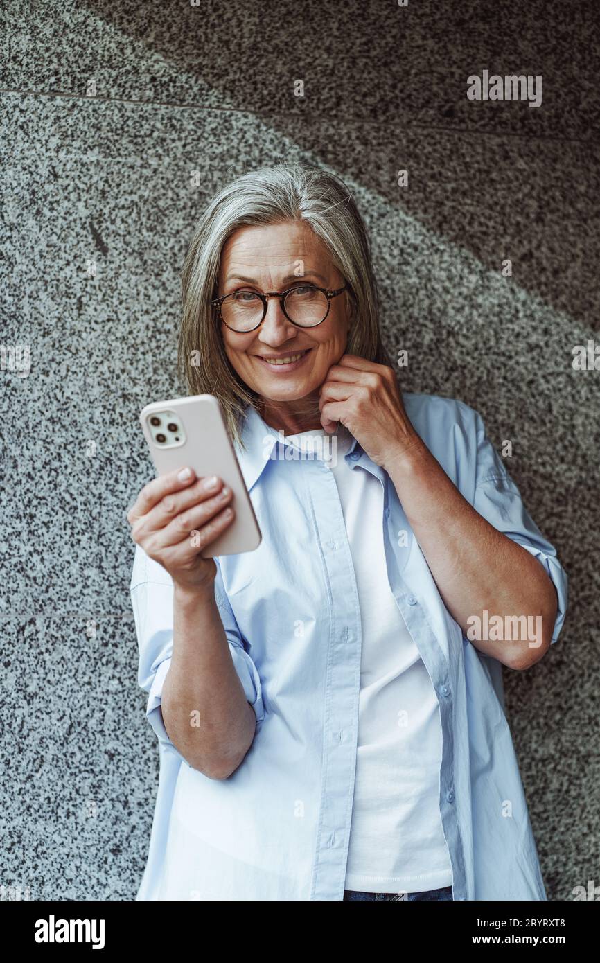 Concept de communication dans la vieillesse, femme âgée mature utilisant le téléphone mobile pour les SMS et les messagers Internet. La femme est active Banque D'Images