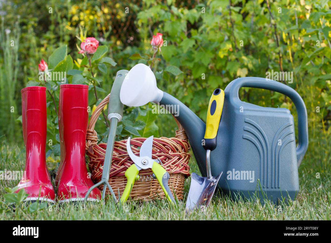 Outils de jardin, bottes en caoutchouc, un panier en osier sur l'herbe Banque D'Images