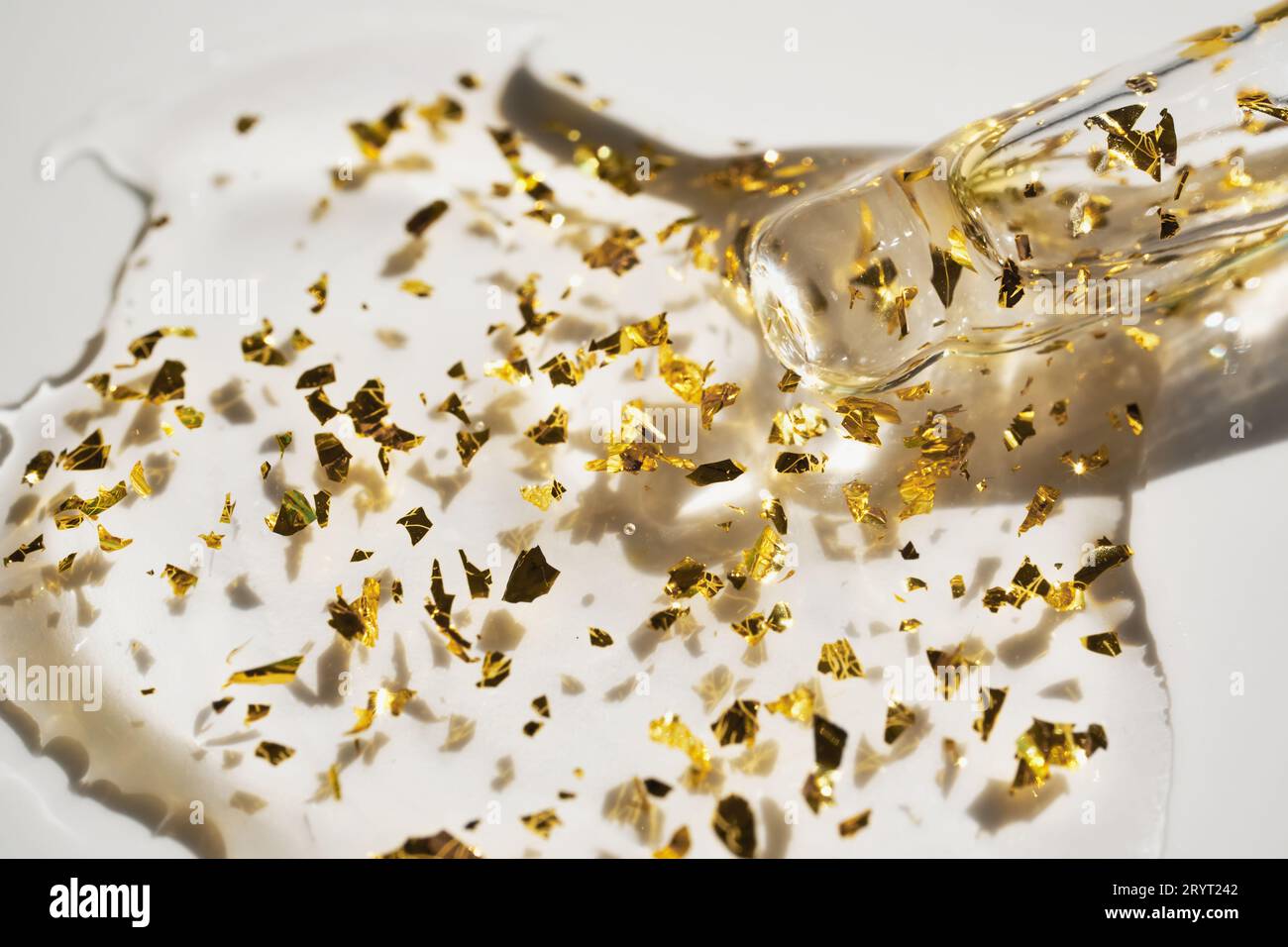 Pipette et goutte de produit cosmétique avec des particules d'or, foyer sélectif Banque D'Images