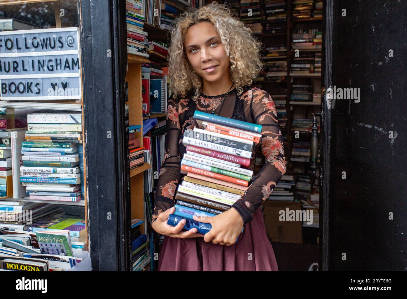 GRAND BRETAGNE / Londres / Hurlingham Books / Femme attrayante tenant pile de livres. Banque D'Images