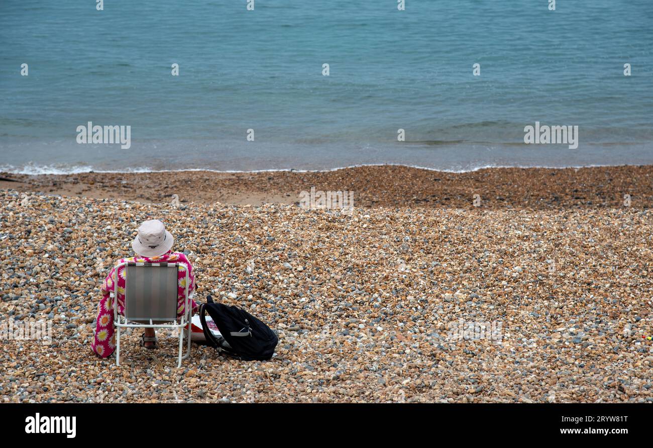 Femme senior se détendant sur une plage de galets. Vacances d'été temps libre des gens Banque D'Images