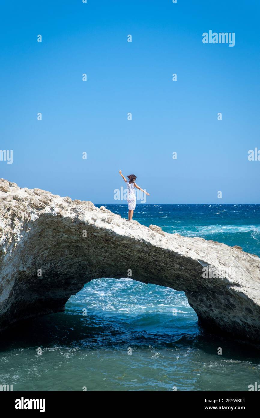 Femme en robe crochet sur une arche en pierre naturelle dans la mer Banque D'Images